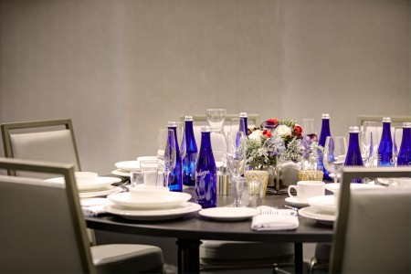 Chairs and round table set with plates, glasses, water bottles and flowers