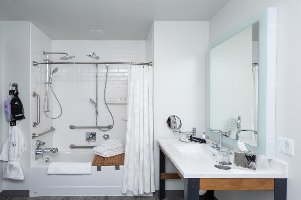 Classic King - mobility-accessible bathroom with tub with grab bars, multiple adjustable shower wands and a shower seat