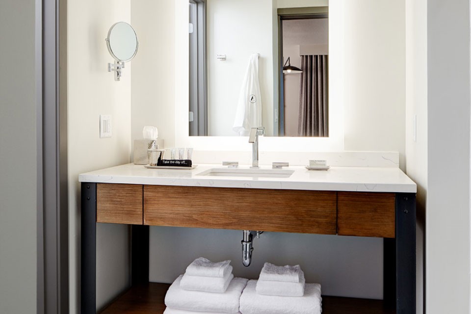Modern bathroom with weathered iron vanity, mirror and luxury bath amenities