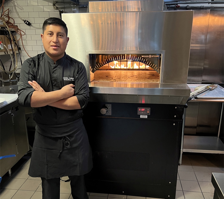 Cristian Asitimbay, executive chef at AKB New York, in front of the AKB pizza oven